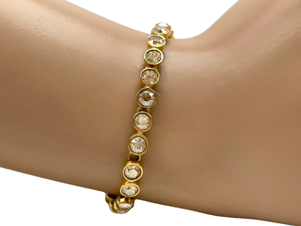 SWAROVSKI CRYSTAL GOLD TONE BRACELET: SWAROVSKI CRYSTAL GOLD TONE BRACELET -GOOD PRE OWNED CONDITION, MISSING SOME STONES (SEE PHOTOS) -STYLISH GOLD TONE BRACELET FEATURING A ROW OF ROUND CUT SWAROVSKI CRYSTALS IN BEZEL SETTINGS. ELEGANT 