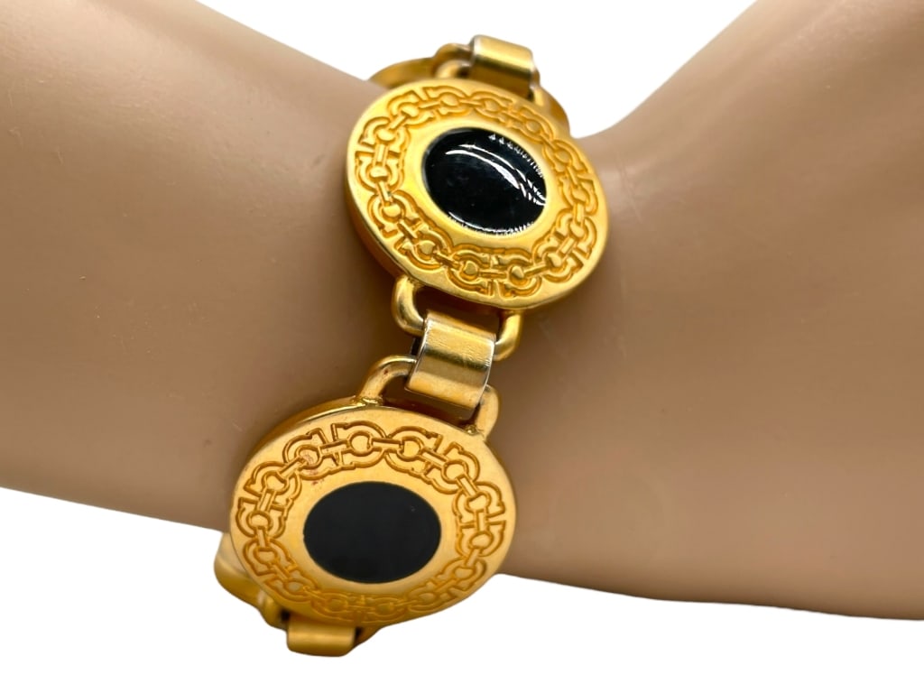 FERRAGAMO GOLD BRACELET OF LINKED MEDALLIONS: FERRAGAMO GOLD BRACELET OF LINKED MEDALLIONS -VERY GOOD PRE OWNED CONDITION -APPROX 8" -MADE IN ITALY -BRACELET FEATURING LINKED MEDALLIONS WITH EMBOSSED INTERLOCKING MOTIF SURROUNDING POLISHED BLACK