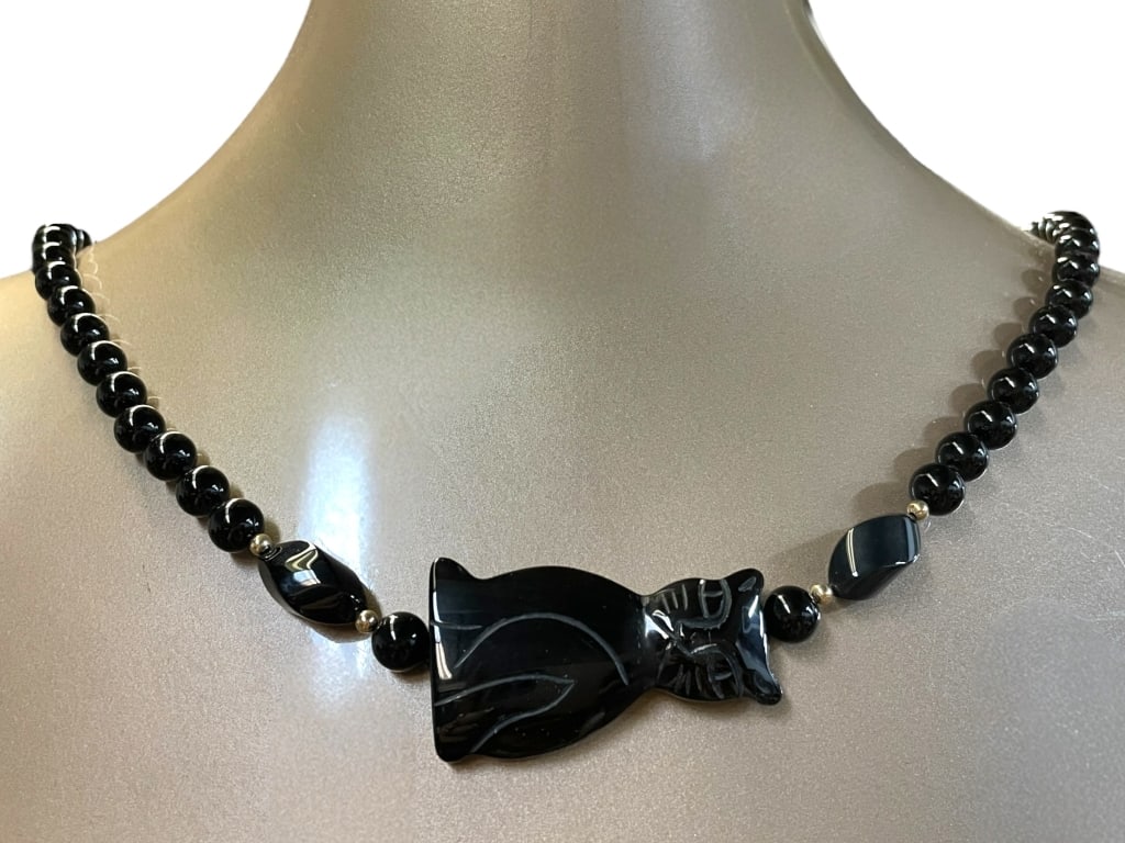 CARVED BLACK ONYX CAT BEAD NECKLACE: CARVED BLACK ONYX CAT BEAD NECKLACE -VERY GOOD PRE OWNED CONDITION -FEATURES A LARGE CENTERPIECE DEPICTING A STYLISED CAT CARVED FROM POLISHED BLACK ONYX, FLANKED BY ROUND AND OVAL ONYX BEADS WITH SIL