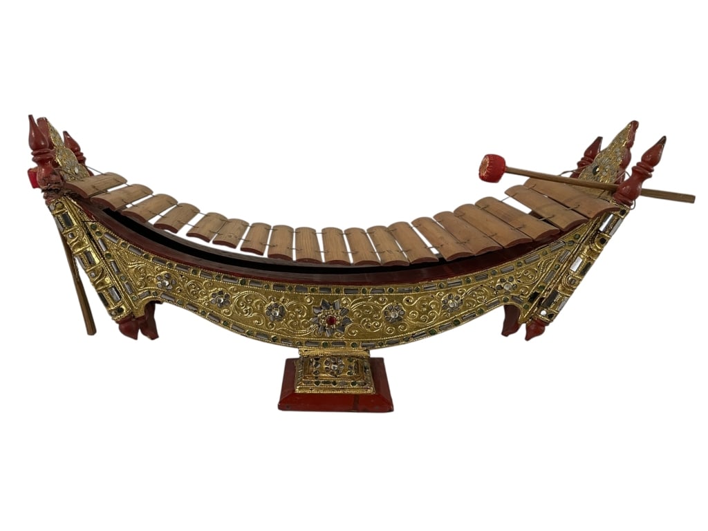 THAI GAMELAN STYLE MINIATURE XYLOPHONE 22": THAI GAMELAN STYLE MINIATURE XYLOPHONE – HANDCRAFTED WITH A CARVED AND GILT WOODEN BODY, EMBELLISHED WITH GLASS INLAY AND FLORAL MOTIFS THROUGHOUT. THE CURVED FRAME HOLDS MULTIPLE BAMBOO KEYS AND IS