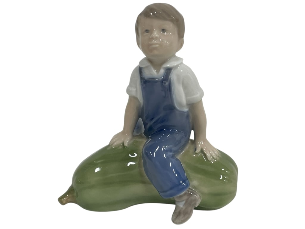 ROYAL COPENHAGEN BOY WITH GOURD PORCELAIN FIGURINE: ROYAL COPENHAGEN BOY WITH GOURD PORCELAIN FIGURINE_x005F -VERY GOOD PRE OWNED CONDITION_x005F -APPROX 4" X 5"_x005F -PORCELAIN FIGURINE OF A YOUNG BOY IN BLUE OVERALLS SITTING ON A LARGE GREEN GOURD.