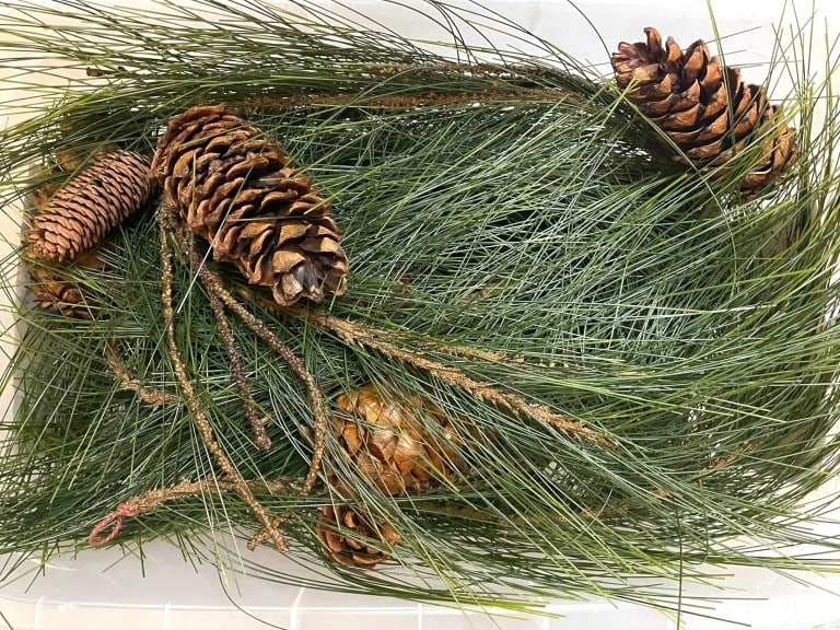BIN OF ARTIFICIAL NATURAL LOOKING PINE BRANCHES: BIN OF ARTIFICIAL NATURAL LOOKING PINE BRANCHES WITH LONG NEEDLES AND PINECONES -GOOD PRE OWNED CONDITION, SEE PHOTOS -FEATURES A VARIETY OF PINECONE SIZES AND SHAPES, IDEAL FOR HOLIDAY DECOR, CRAFT P