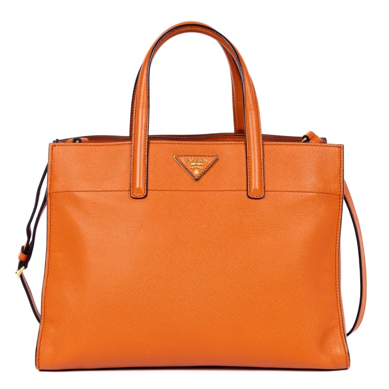 PRADA CABAS ORANGE SAFFIANO LUX LEATHER HANDBAG: The Prada Crossbody Cabas is a vibrant piece crafted in orange Saffiano Lux calf leather. Featuring gold-tone hardware and a detachable strap, this tote-style handbag offers both sophistication and pr