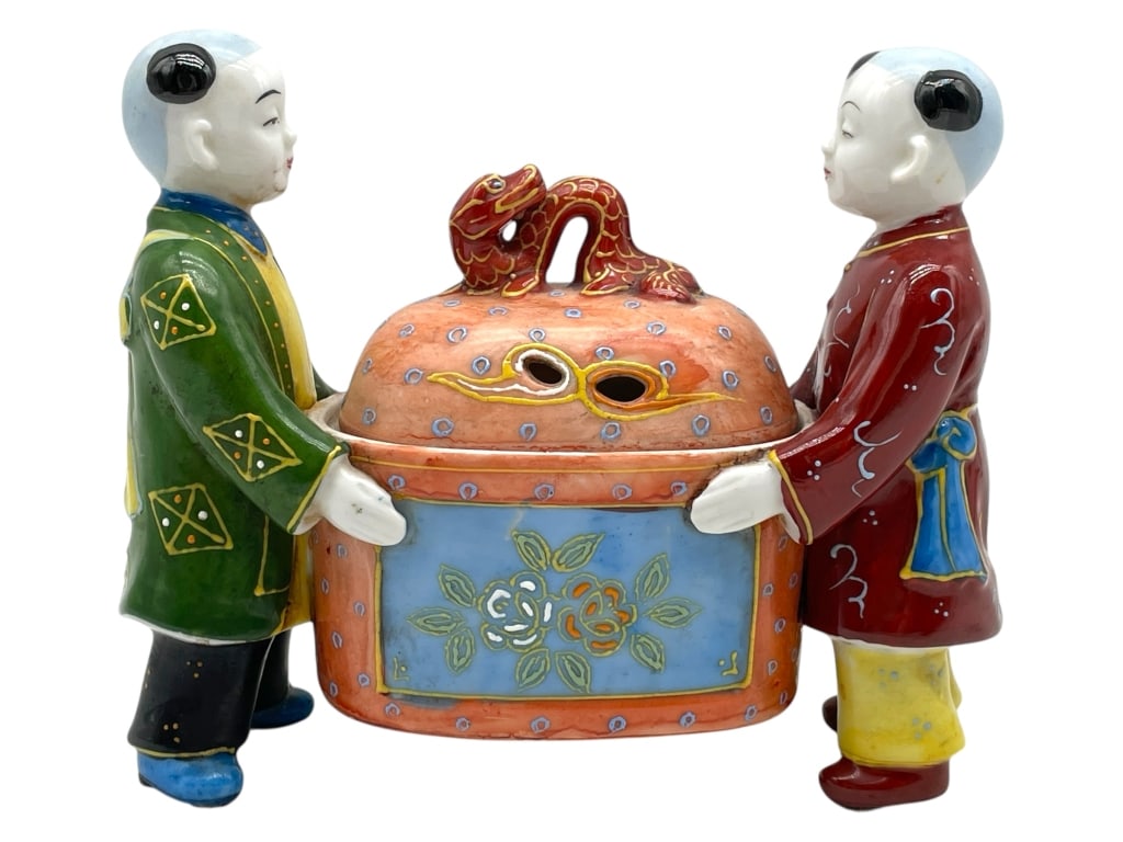 WILDWOOD ACCENTS PORCELAIN FIGURAL CENSER: WILDWOOD ACCENTS PORCELAIN FIGURAL CENSER – BOYS HOLDING DRAGON-TOPPED URN -Very good pre owned condition -Approx 6"h x 6.5"w x 2"d -Porcelain censer depicting two boys in traditional attire carryin