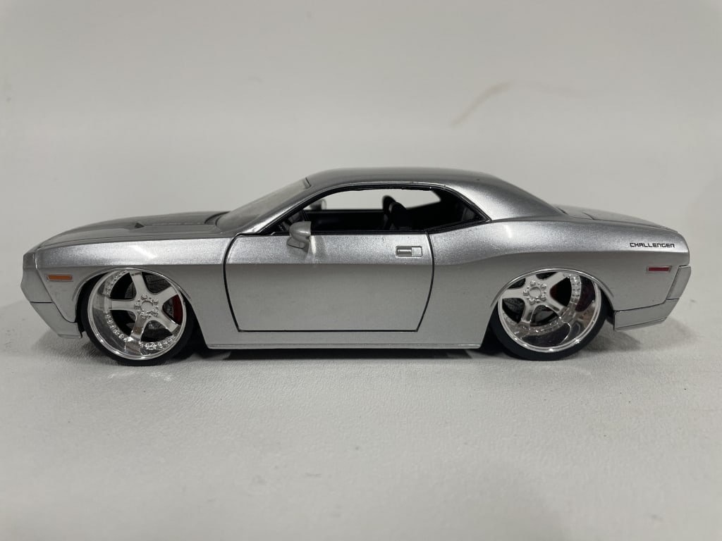 DODGE CHALLENGER DIECAST MODEL CAR 8": DODGE CHALLENGER DIECAST MODEL – SILVER MUSCLE CAR EDITION -Good pre owned condition -Approx 8"l -Sleek and powerful Dodge Challenger diecast model finished in metallic silver, featuring a low stanc