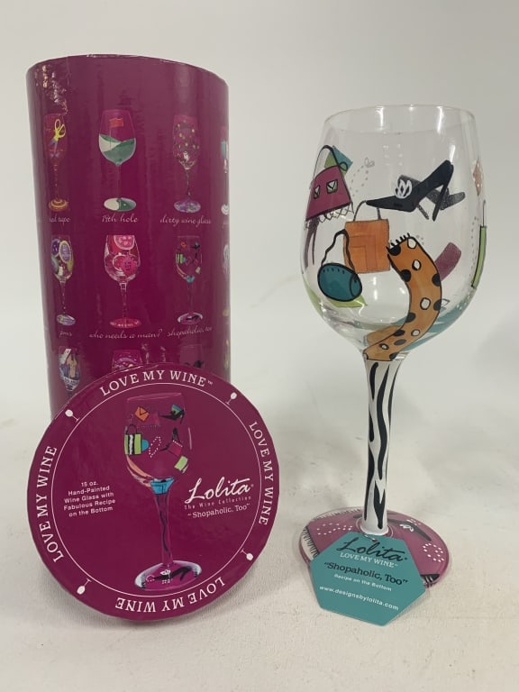 NEW IN BOX LOLITA SHOPAHOLIC PAINTED WINE GLASS: - new in box - features fashion decor - handpainted By bidding on this listing, you understand and agree to be bound by the terms and conditions of DejaVu Auctions. * For local pick up or third party