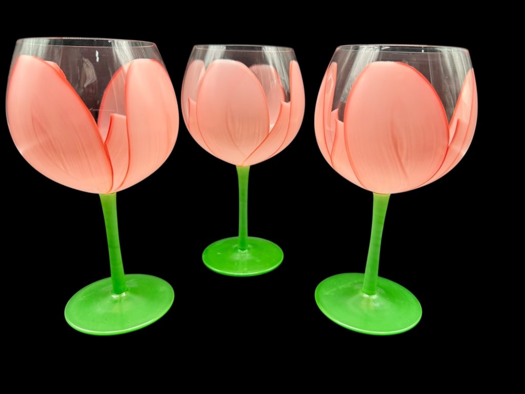 SIGNED GLORIA vANDERBUILT HANDPAINTED GOBLETS: SET OF THREE HAND-PAINTED TULIP STEMMED GOBLETSA whimsical and beautifully crafted set of three tulip-inspired stemmed goblets, each featuring soft pink hand-painted petals forming the bowl and bright