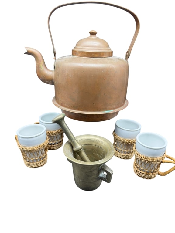 VTG COPPER KETTLE, BRASS MORTAR & PESTLE, AND MUGS: A rustic kitchenware grouping including a vintage copper kettle with carry handle, a heavy brass mortar and pestle set, and four ceramic mugs wrapped in charming wicker sleeves. Ideal for farmhouse, p