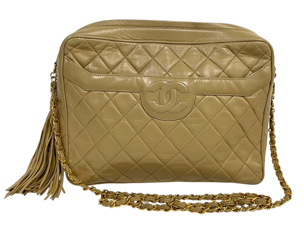 CHANEL CLASSIC QUILTED LEATHER CAMERA BAG: CHANEL CLASSIC QUILTED LEATHER CAMERA BAG WITH TASSEL AND GOLD CHAIN STRAP -Very good owned condition -Approx 10"l x 3"w x 7"h -Iconic vintage Chanel camera bag crafted in buttery beige quilted lambsk