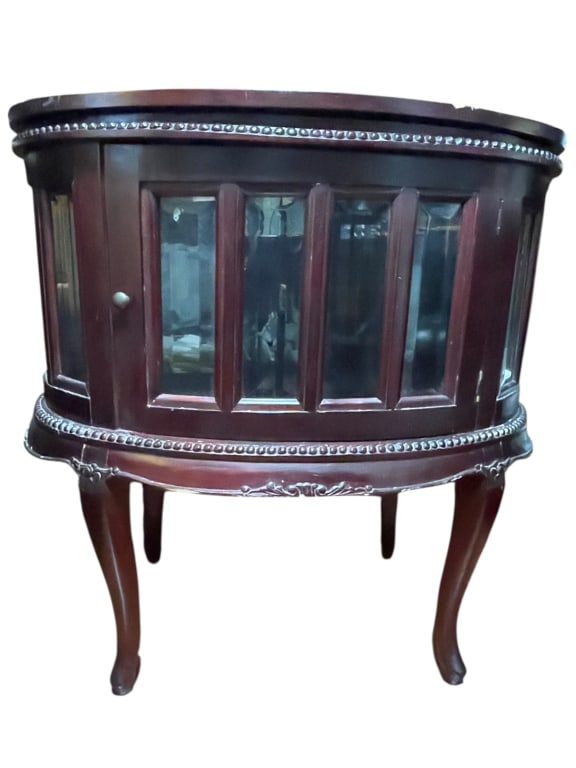OVAL GLASS-FRONT DISPLAY CABINET 29": OVAL GLASS-FRONT DISPLAY CABINET WITH CARVED WOOD BASE -Elegant oval display cabinet featuring a rich mahogany-toned wood finish with paneled glass sides and a curved glass-front door, raised on grace