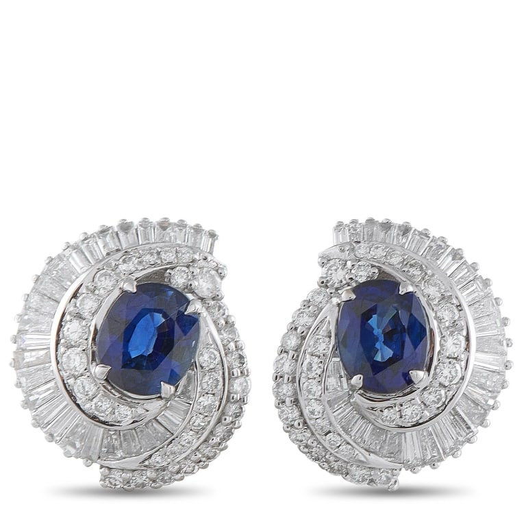 PLATINUM 1.50CT DIAMOND AND SAPPHIRE STUD EARRINGS: Rich color and a swirl of brilliance mark these earrings. Each features an oval sapphire in a deep, royal blue hue, embraced by a spiraling halo of diamonds in both round and baguette cuts. The diamon
