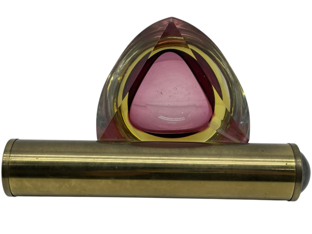 BRASS TELESCOPE AND ART GLASS TRINKET DISH: BRASS TELESCOPE AND ART GLASS TRINKET DISH -Decorative pairing featuring a solid brass telescope with cylindrical form and dark end caps, displayed alongside a sculptural art glass trinket dish in a t