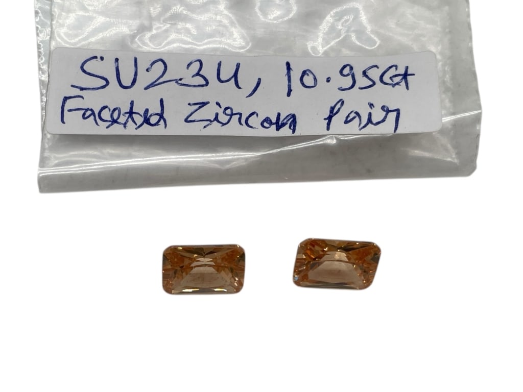 FACETED ZIRCON PAIR TOTALING APPROX 10.95 CARATS: FACETED ZIRCON PAIR TOTALING APPROX 10.95 CARATS -Matched pair of faceted zircon gemstones with a combined total weight of approximately 10.95 carats. These rectangular step-cut stones display warm go