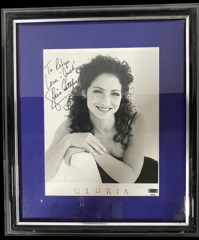"Queen of Latin Pop," Gloria Estefan HAND SIGNED: This framed photograph features a hand-signed promotional portrait of the Grammy-winning "Queen of Latin Pop," Gloria Estefan. Item Identification Subject: Gloria Estefan, a world-renowned singer-song