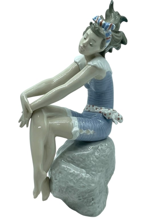 LLADRO SEASIDE BATHER GIRL PORCELAIN FIGURINE: *for alternative shipping options please go to www.dejavuauctionshipping.com -LLADRO SEASIDE BATHER GIRL PORCELAIN FIGURINE APPROX 8" H -Elegant Lladró porcelain figurine depicting a seated seaside b