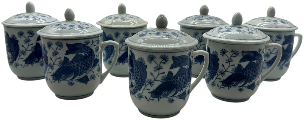 7 VINTAGE ASIAN PORCELAIN LIDDED KOI FISH TEA CUPS: SET OF 7 BLUE & WHITE PORCELAIN LIDDED TEA CUPS WITH KOI FISH MOTIF Charming set of six blue and white porcelain lidded tea cups featuring a traditional koi fish motif surrounded by delicate botanical