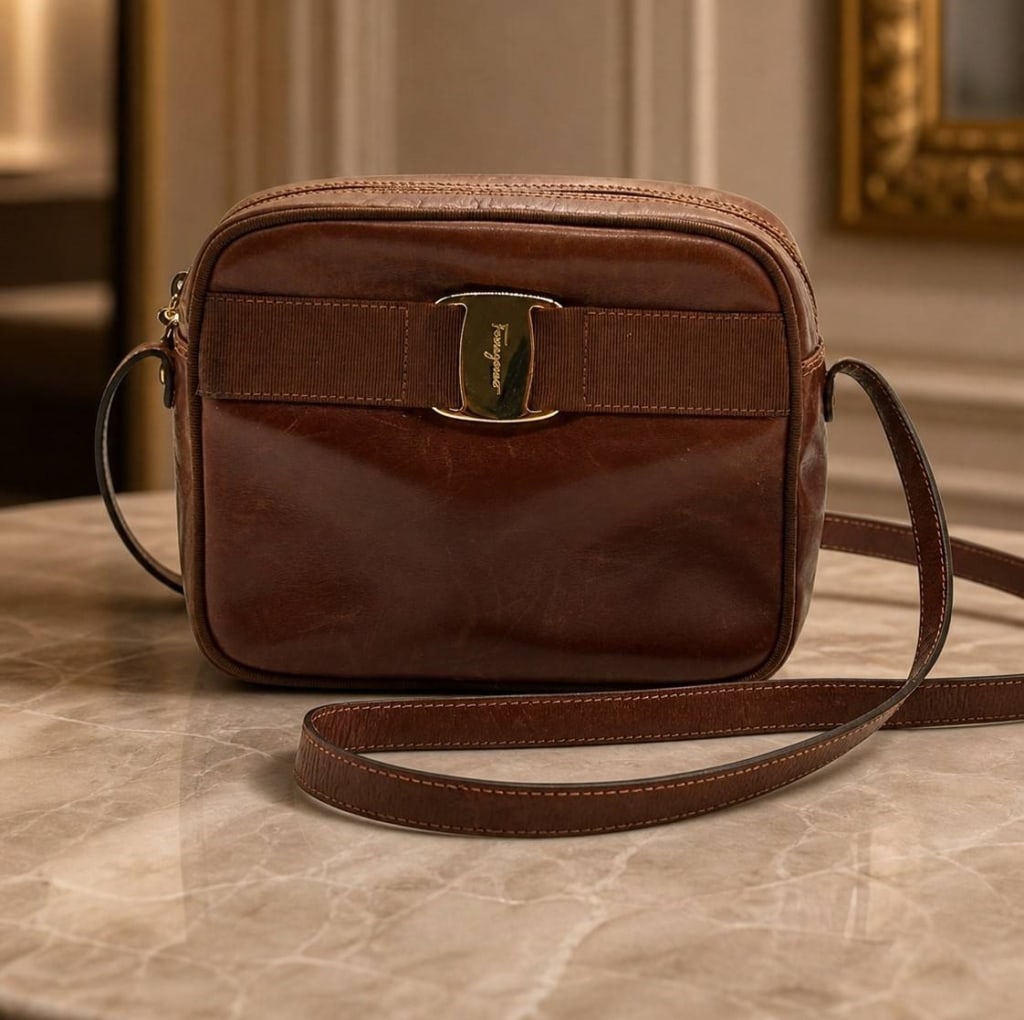 SALVATORE FERRAGAMO BROWN LEATHER VARA BOW CROSSBO: Classic Salvatore Ferragamo brown leather crossbody bag featuring a structured rectangular silhouette, zip-top closure, gold-tone Ferragamo hardware, signature Vara-style bow detail across the front, 
