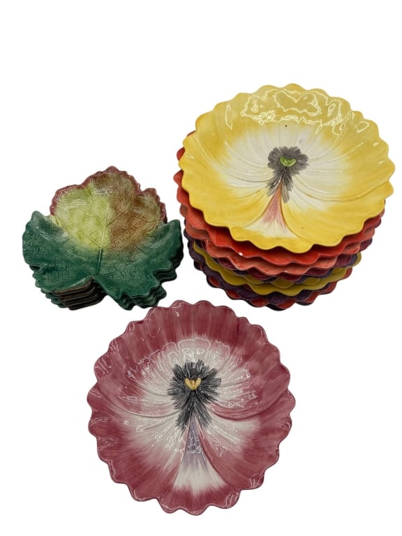 FITZ FLOYD FLORAL AND LEAF PLATES SET: 10 ceramic plates with a floral motif in yellow and purple tones, and 4 ceramic plates in a green leaf design. Shipping available at www.DeJaVuAuctionShipping.com. By bidding in this auction you agree