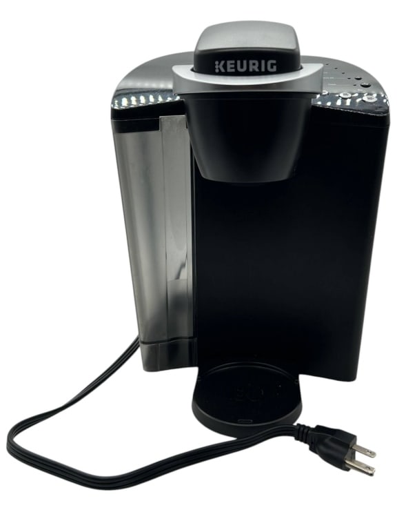 KEURIG SINGLE SERVE COFFEE MAKER BLACK: Keurig single serve coffee maker in black finish with silver-tone accents, removable water reservoir, power cord, drip tray, and front brewing area. Control panel includes indicator lights for Add
