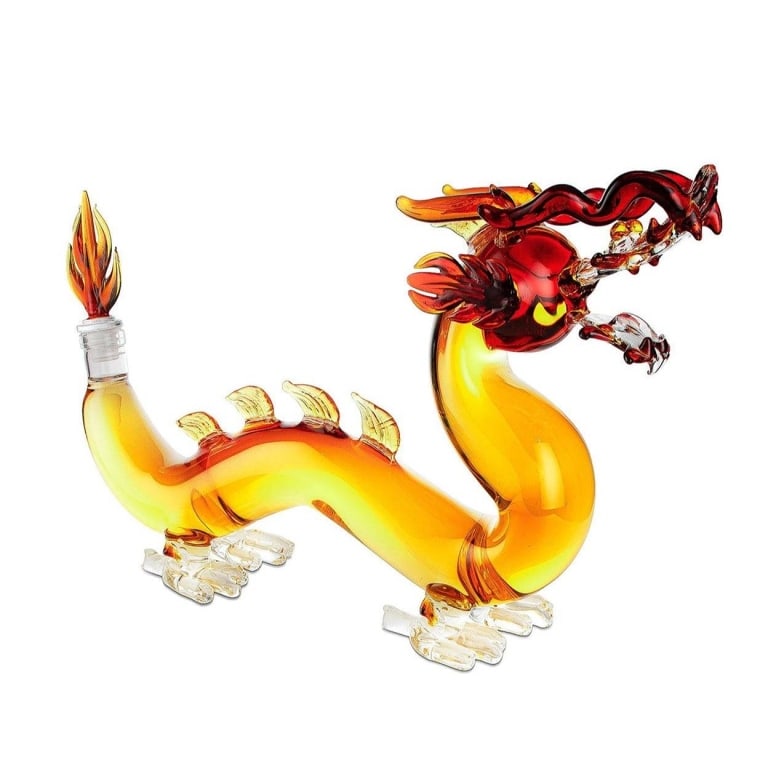 GLASS DRAGON DECANTER NEW IN BOX: Glass dragon-shaped decanter measuring 16 inches in length and 10 inches in height. Features detailed clear and amber colored glass work, with flame stopper and sculpted features. Shipping Available a