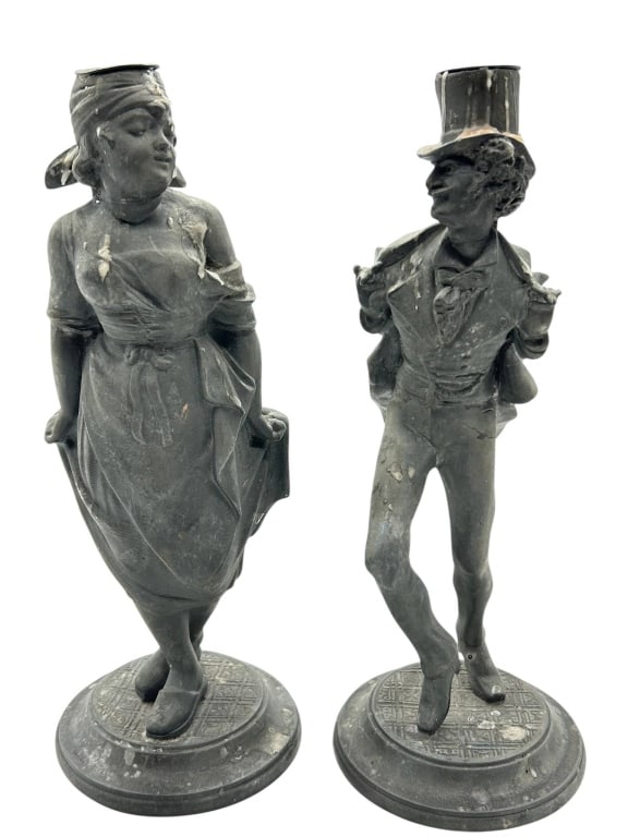 ANTIQUE FIGURAL BLACK METAL CANDLESTICK PAIR 12": Pair of antique figural candlesticks featuring a charming Victorian-style gentleman and lady, each modeled in dark patinated metal with detailed period dress, expressive faces, and round decorative ba