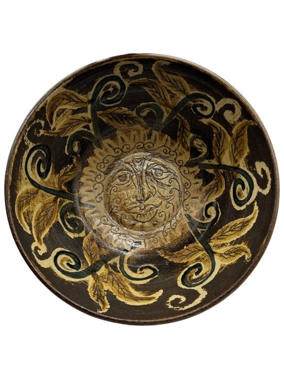 SIGNED STUDIO POTTERY SUN FACE DECORATIVE BOWL 11": Decorative signed studio pottery bowl featuring a rich earthy brown glaze with hand-decorated cream, tan, and dark green scrolling vine and leaf designs throughout the interior and exterior. The cente