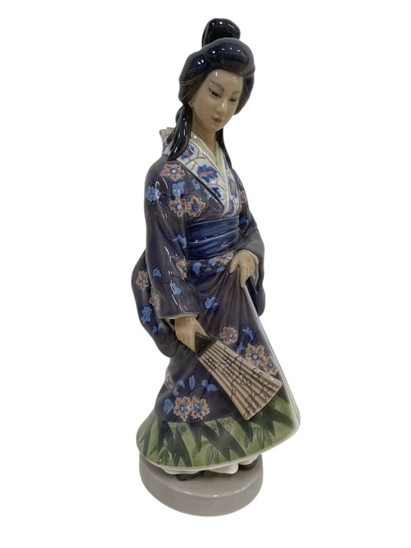 PORCELAIN JAPANESE GEISHA FIGURINE 13": This porcelain figurine depicts a Japanese woman or geisha in a richly decorated kimono, finished in deep blue, gray, green, and floral enamel accents. She is posed holding a fan or parasol form,