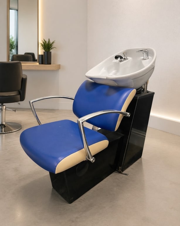 MODERN BLUE VINYL SALON SHAMPOO BACKWASH CHAIR: Contemporary salon shampoo backwash chair featuring vivid blue vinyl upholstery, sleek chrome-finished armrests, and an integrated white ceramic shampoo basin with faucet and spray fixture. This profe