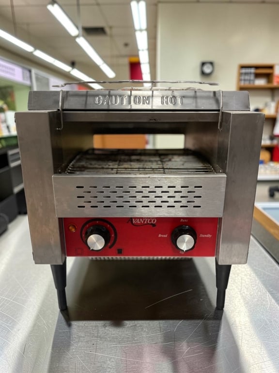 AVANTCO COMMERCIAL COUNTERTOP CONVEYOR TOASTER: Compact commercial countertop conveyor toaster by Avantco, featuring a stainless steel body, front control panel, adjustable heat settings, and bun/bread selector knob. Designed for fast-paced restaur