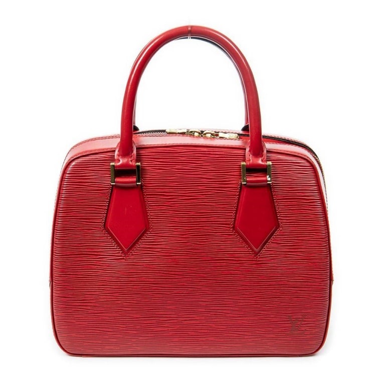 LOUIS VUITTON RED EPI LEATHER HANDBAG: Louis Vuitton handbag crafted from signature red Epi leather. Features dual rolled handles, gold-tone hardware, structured silhouette, and zip-top closure. The interior is lined in matching red. Excel