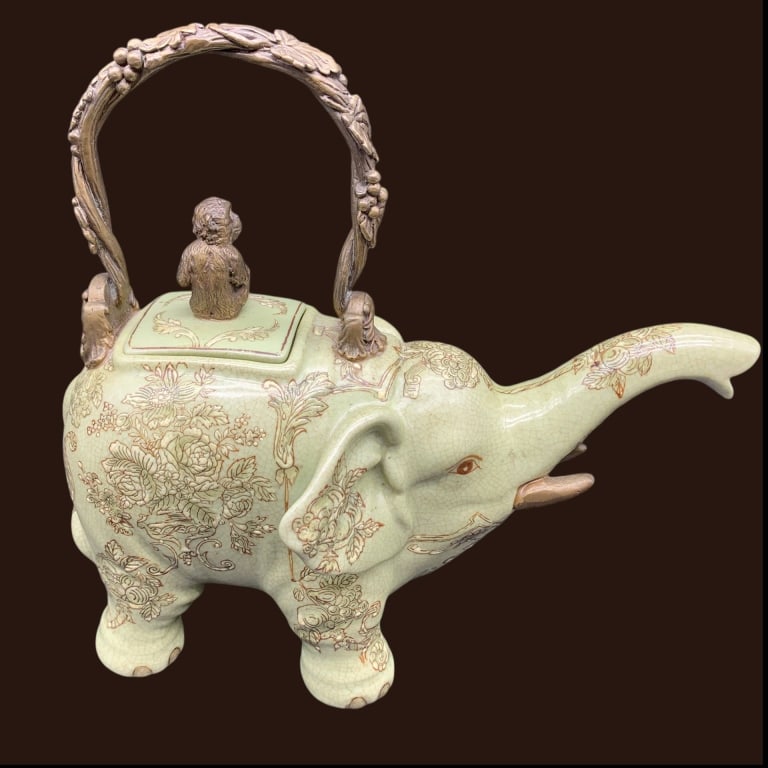 CHINESE CELADON ELEPHANT TEAPOT PORCELAIN: Chinese celadon porcelain teapot shaped as an elephant, with floral and animal motif designs. Features a sculpted handle and a figure on the lid. Measures approximately 10 inches wide and 9 inches tal