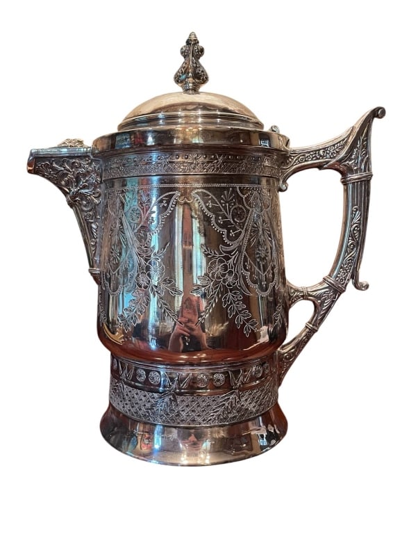 VICTORIAN QUADRUPLE SILVER PLATE COFFEE POT 10": Antique Victorian silver Quadruple plate pitcher. Features ornate floral engravings, intricate handle, hinged lid, and raised decoration. Stands approximately 10 inches tall. Some wear consistent with