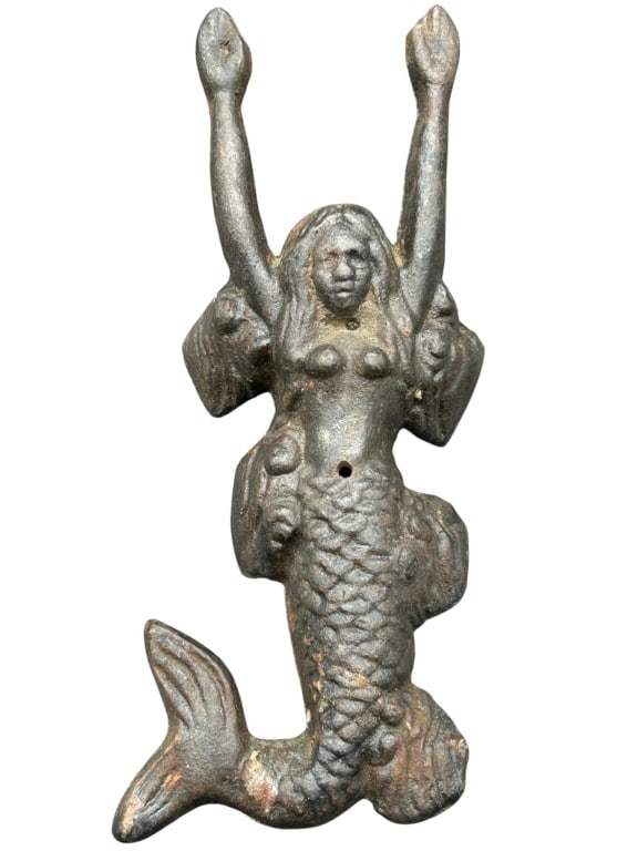 CAST IRON MERMAID FIGURINE WALL DECOR 9": Vintage cast iron mermaid figurine with raised arms, approximately 9 inches long. Features detailed scales and long hair. Likely used as decorative wall art or nautical accent. Minor wear consistent w