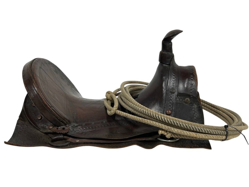VINTAGE WESTERN LEATHER SADDLE WITH ROPE 19": This vintage Western saddle features worn, tooled brown leather and comes with a coiled lasso rope. Decorative stitching and aged patina add to its character. Saddle measures approximately 19" long by