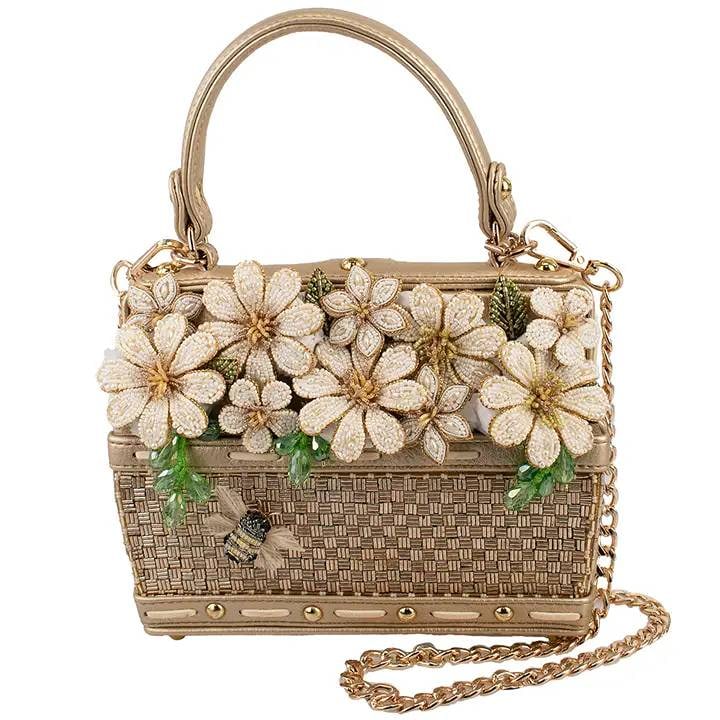 NEW MARY FRANCES BASKET OF SUNSHINE BAG: Sweet as springtime, this charming handbag is adorned with sparkling blossoms and a tiny buzzing bee ready to steal your heart. With its woven detailing and golden shine, it’s the perfect little gar