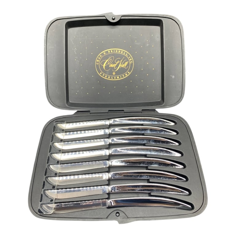 CARLISLE HALL STAINLESS STEELSMITHS KNIFE SET IN C: Eight knives by Carlisle Hall Steelsmiths in a fitted black hard case. Each knife is crafted from stainless steel. The case features a gold-tone medallion with maker details. Approximately 11" wide | 