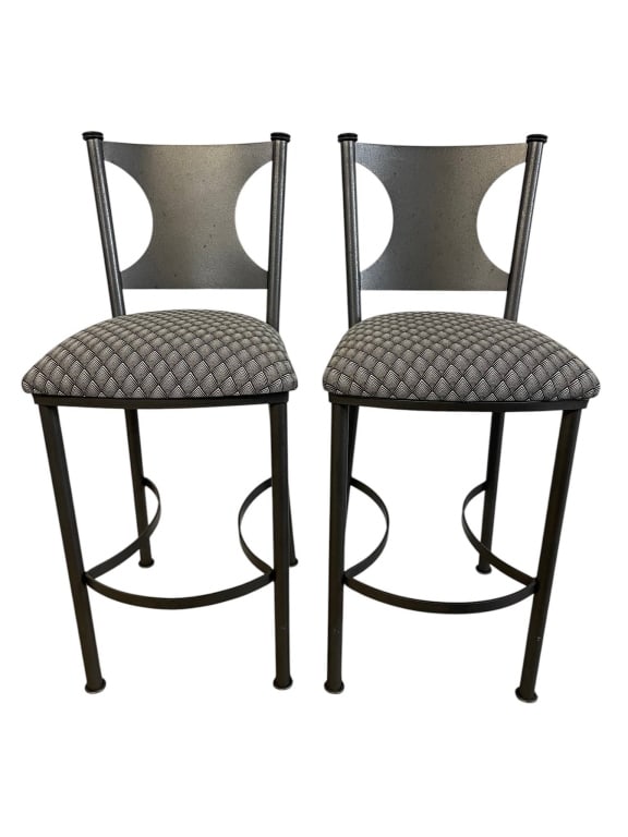 PAIR METAL BAR STOOLS WITH UPHOLSTERED SEATS 43": Pair of contemporary metal bar stools featuring dark gunmetal/black tubular frames, curved circular footrests, and decorative back panels with bold round cutout details. Each stool has a padded uphols