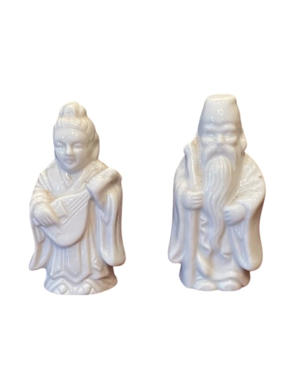 BLANC DE CHINE STYLE ASIAN WHITE CERAMIC FIGURINES: Small white glazed ceramic figurines, each depicting a traditional figure in robes. The pair measures approximately 3 to 4 inches tall, with fine details and a smooth finish. Good condition overall wi