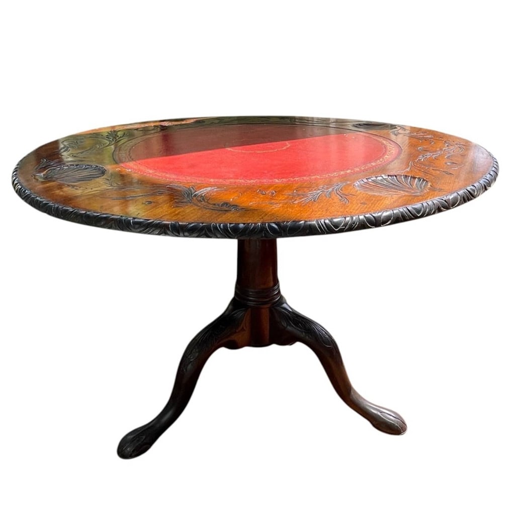 ANTIQUE CARVED MAHOGANY TABLE 39": Antique carved mahogany round tilt-top occasional table featuring a richly carved circular top with shell, floral, and foliate decoration, gadrooned carved rim, and inset red leather writing surface w