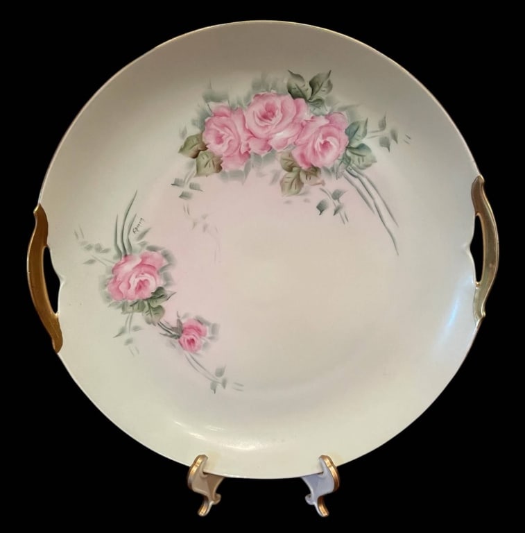KPM GERMANY PORCELAIN CAKE PLATE WITH ROSES 10": Elegant KPM Germany porcelain cake plate featuring hand-painted pink roses with gold-trimmed dual handles. Approximate diameter is 10 inches. Marked on the underside. Delicate, collectible decorative 