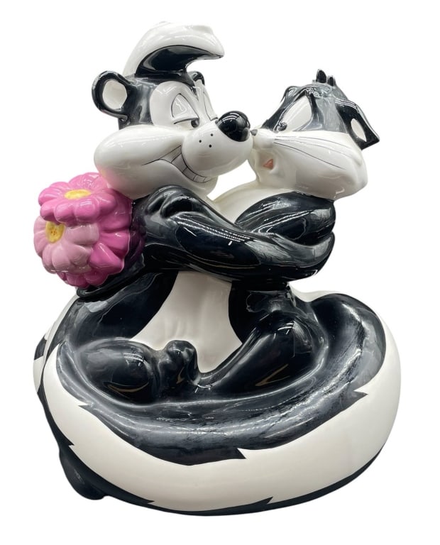 PEPE LE PEW AND PENELOPE COOKIE JAR 12": This Warner Bros. Studio Store ceramic cookie jar features Pepe Le Pew and Penelope. The vibrant piece measures about 12" inches tall and comes with its original box, displaying minimal wear. A charmi
