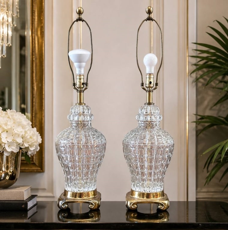 PAIR OF CUT GLASS TLAMPS ON BRASS BASES 33": This pair of cut glass table lamps features intricately patterned glass bodies mounted on ornate brass bases. Each lamp stands approximately 28 inches tall and 7 inches wide. Both cords and hardware a