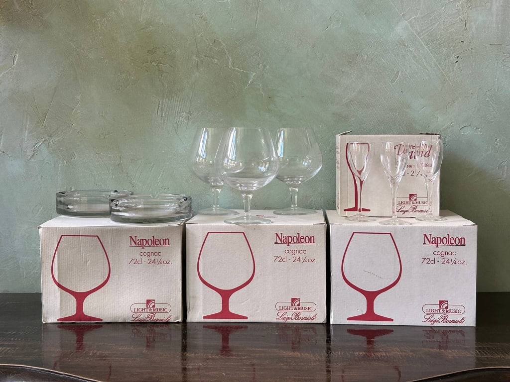 19 PCS LUIGI BORMIOLI GLASSWARE AND ASHTRAY LOT: Vintage decorative glassware lot featuring Luigi Bormioli Light & Music boxed Napoleon cognac glasses, Michelangelo David liqueur glasses, and two matching clear glass ashtrays. The group includes