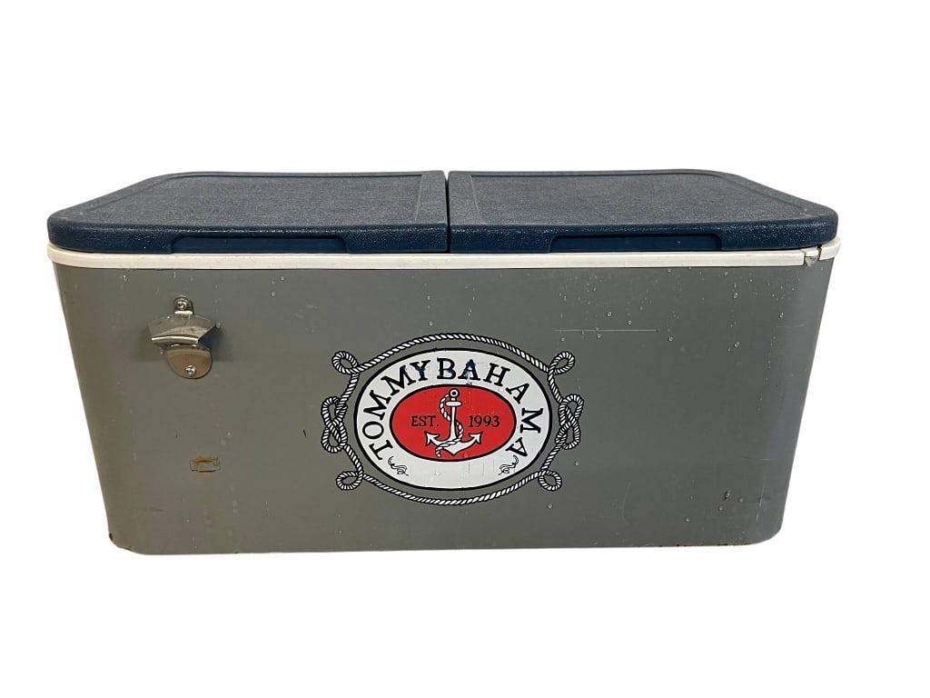 TOMMY BAHAMA COOLER WITH BOTTLE OPENER 30": Tommy Bahama cooler featuring a prominent logo on the front. Includes a built-in bottle opener and handles on the sides. The cooler has a hinged lid and is designed for outdoor use and beverage storag