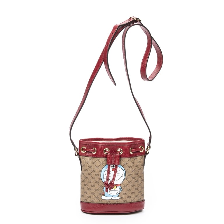 GUCCI X DORAEMON MINI BUCKET BAG: This limited-edition Gucci x Doraemon Mini Bucket Bag celebrates the iconic collaboration between Gucci and the beloved Japanese character. Crafted in brown and red Microguccissima coated canvas,