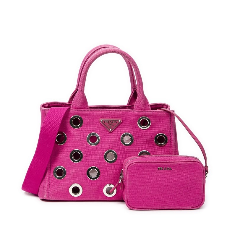 PRADA GROMMET CANAPA CANVAS SHOULDER BAG: The Prada Small Grommet Canapa Tote is a bold and stylish statement piece crafted in vibrant fuchsia pink Canapa canvas. Accented with signature silver-tone grommet detailing, this eye-catching tote