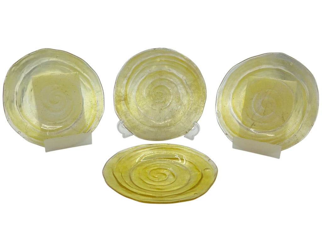 4 LOT OF YELLOW SWIRL ART GLASS PLATES 9": Decorative lot of four yellow art glass plates featuring translucent pale yellow glass with raised spiral swirl designs, rounded irregular edges, and visible bubble inclusions throughout. The plates