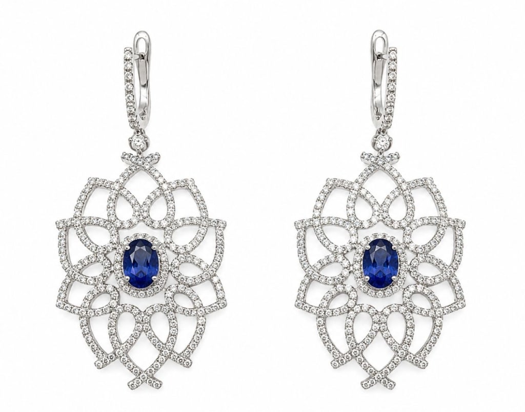 PAIR OF 14K WHITE GOLD TANZANITE DIAMOND EARRINGS: Pair of 14K white gold drop earrings featuring two natural oval-cut tanzanites with a combined weight of approximately 1.60 carats. The openwork floral design is accented by round brilliant-cut diamon