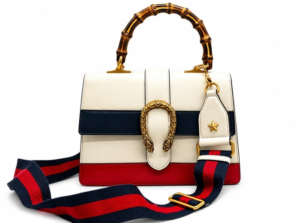 GUCCI DIONYSUS BAMBOO TOP HANDLE BAG 12": Gucci Dionysus top handle handbag crafted in smooth leather with a striking white, navy blue, and red color-block design. This structured bag features the iconic antiqued tiger head horseshoe closure 