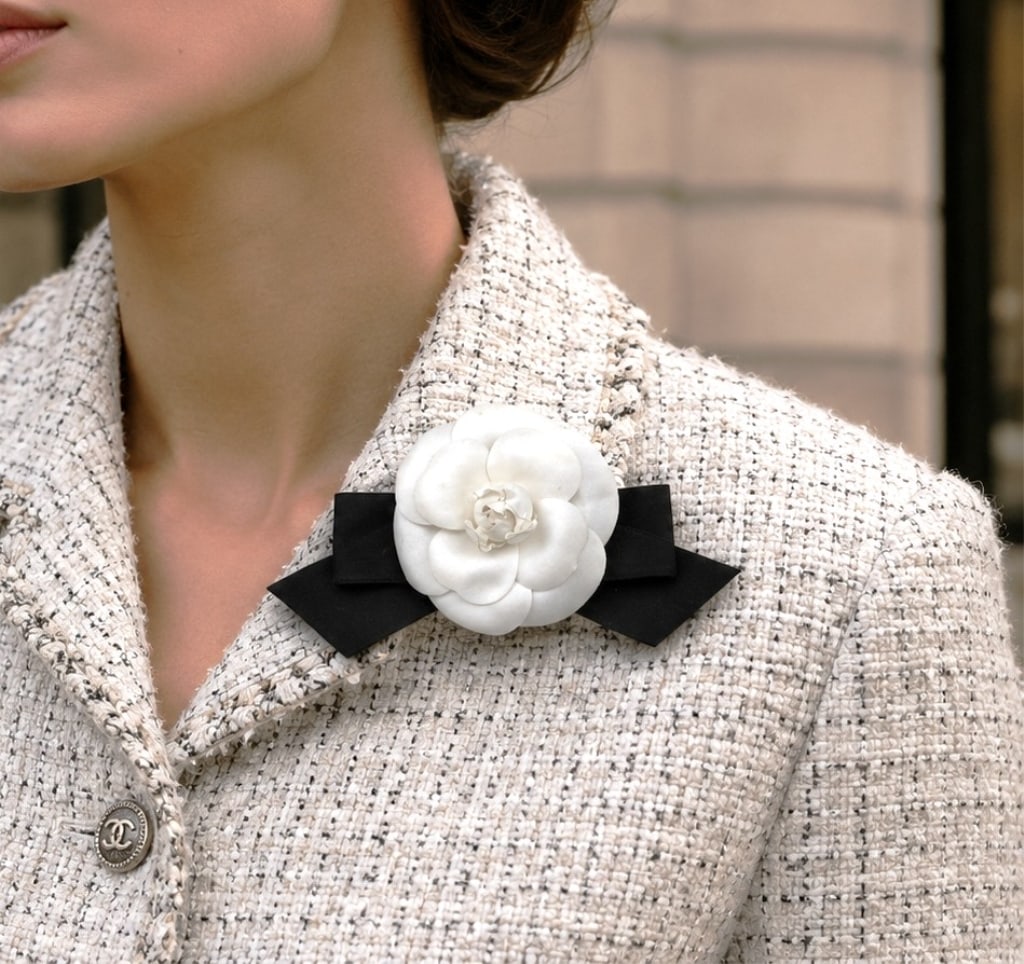 CHANEL CAMELLIA FLOWER BROOCH W BOX 8": Chanel's iconic and coveted white camellia flower brooch featuring layered fabric petals with a black ribbon bow accent and gold-tone Chanel maker's tag marked Made in France. The brooch retains its o